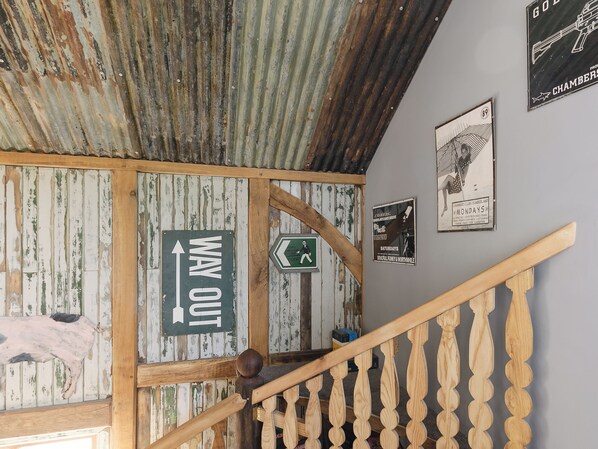 A rustic interior with a wooden staircase, a 'WAY OUT' sign, and a 'MONDAYS' poster on the wall. - 4 bedroom accommodation in Longhope, near Gloucester (Longhope, near Gloucester)