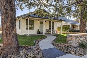 Einbungalow mit überdachter Veranda, einer Steinsichtmauer und einem Weg zum Eingang.