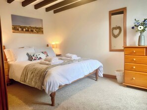 Ein Schlafzimmer mit einem Bett, einem Schminktisch, einem Spiegel, einem Wandbild und einer Nachttischlampe.