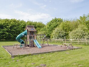 Un parque infantil con tobogán, zona de escalada y mesas de picnic.