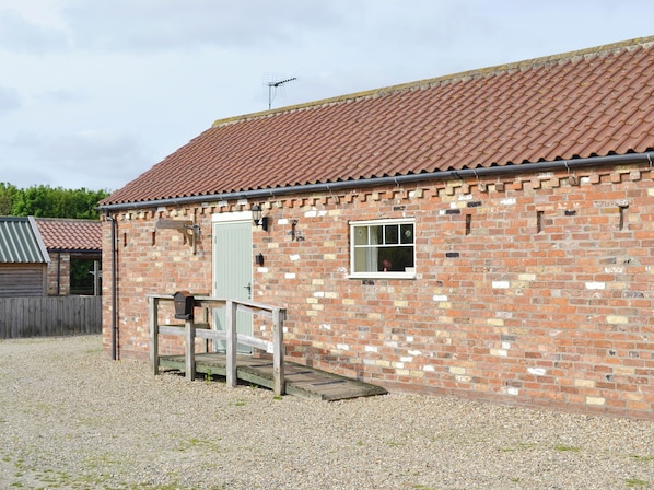 A brick building with a tiled roof, a small window, and a door.