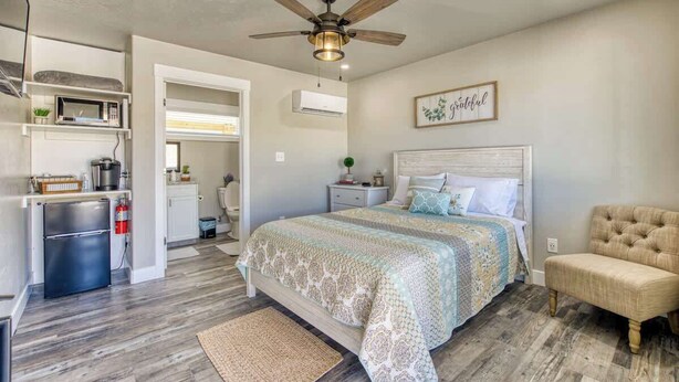 A bedroom with a bed, a ceiling fan, a bedside table, and a chair. - Kanab Retreat by National Parks, Quiet Suite #1 (Kanab)