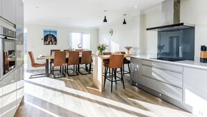 Une cuisine moderne dotée d’un îlot central, d’un coin repas avec des chaises et d’une grande fenêtre.