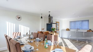 Un coin repas avec une table en bois dressée pour quatre personnes, entourée de chaises rembourrées.
