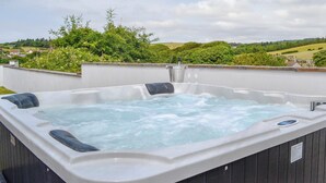 A hot tub on a rooftop with a view of a green landscape.