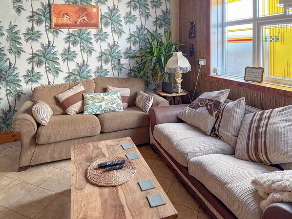 A living room with two sofas, a coffee table, and a lamp. There is a painting on the wall and a sign that says "Welcome to our home".