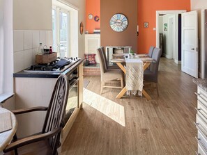 A modern kitchen with a gas stove, wooden cabinets, and a dining area with a table and chairs.