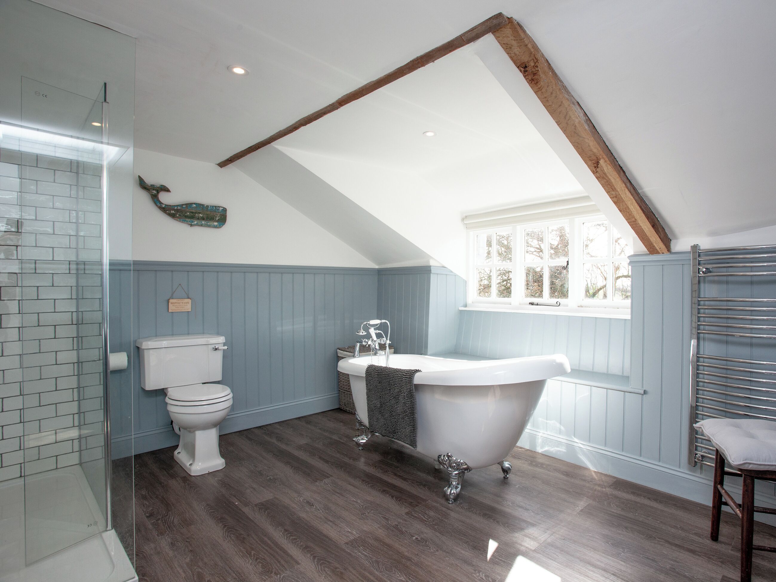 A bathroom with a white toilet, a freestanding bathtub, and a glass shower enclosure.