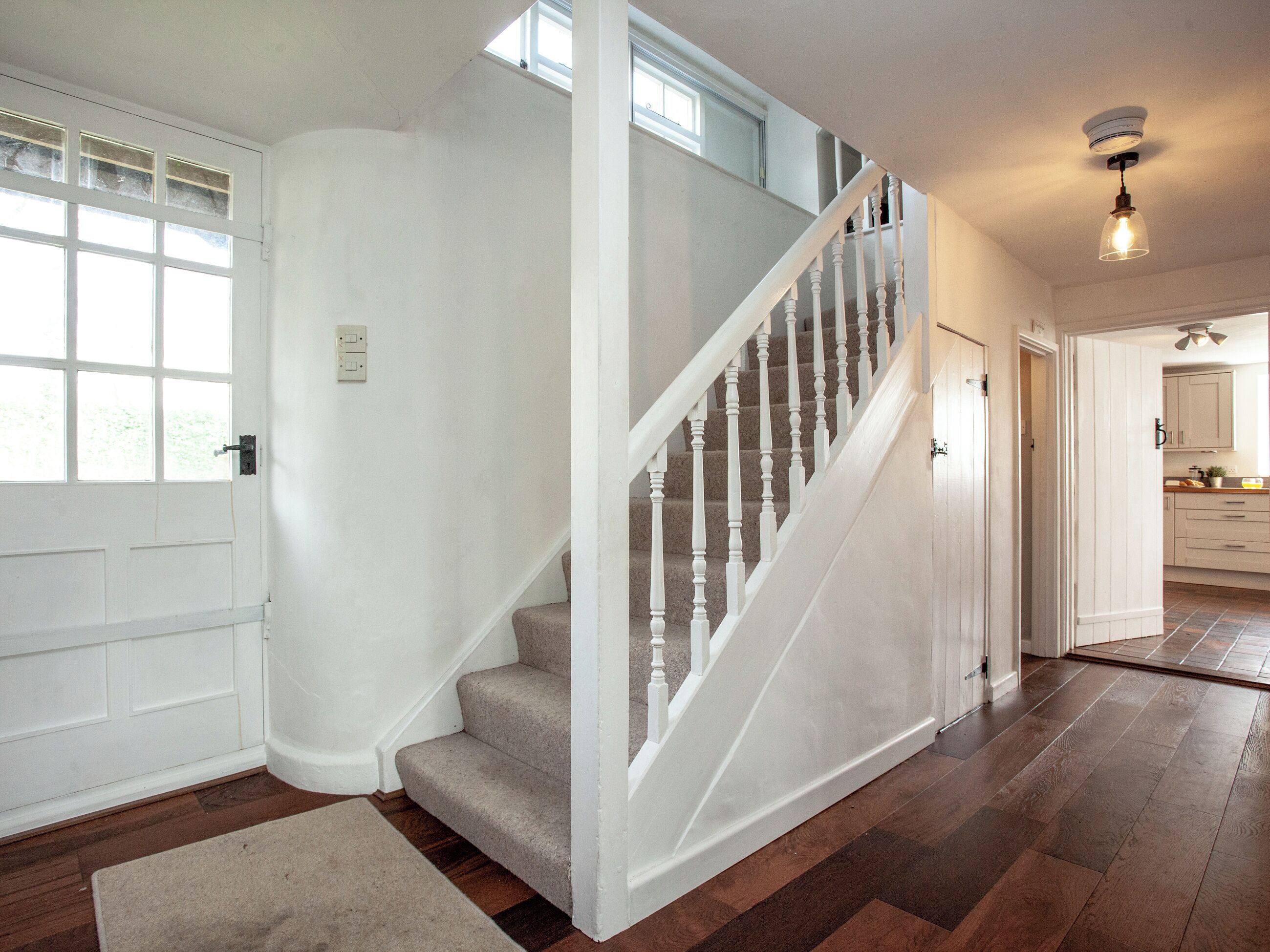 Eine Treppe mit weißen Balustraden und Teppichstufen, die zu einer zweiten Etage führt.