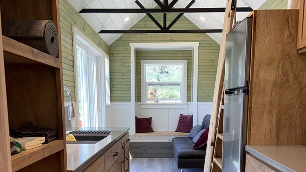A compact kitchen with wooden cabinets, a built-in bench, and a window overlooking greenery.
