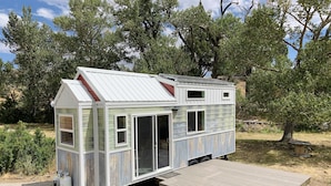 A small, single-story mobile home with a metal roof, a front porch, and a side door.