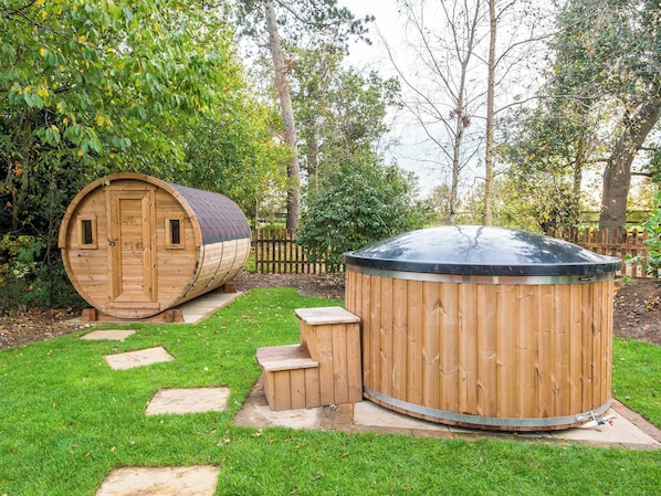 Un bain à remous en bois et une structure en forme de tonneau dans un jardin.