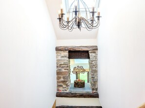 A chandelier with multiple light fixtures, a stone-framed window, and a decorative tree sculpture.