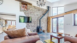 Un salón acogedor con pared de piedra, chimenea, sofá y televisor.