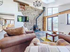 A cozy living room with a stone wall, a fireplace, a sofa, and a television.