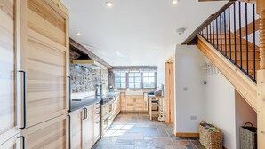 Una cocina con armarios de madera, suelo de piedra y vistas al comedor.