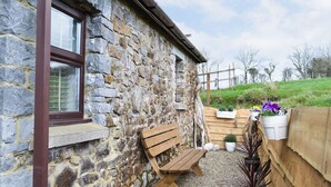 A stone building with a wooden bench and potted plants. - 1 bedroom accommodation in Marros, near Amroth (Marros, near Amroth)