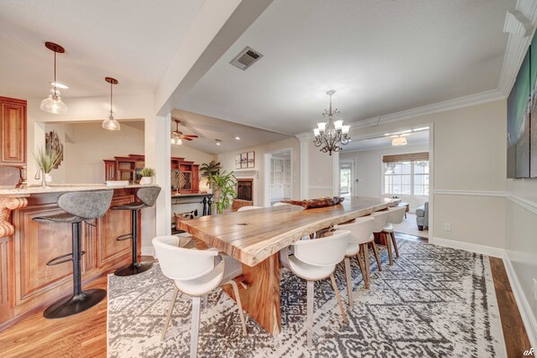 A spacious kitchen with a large wooden island, white bar stools, and pendant lighting.