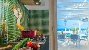 A kitchen with green tiles, a red pot, fresh vegetables, and a bottle of olive oil. - Villa Vittoria - Waterfront house (Augusta)