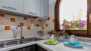 Una cocina con un lavamanos, armarios y una ventana con flores.