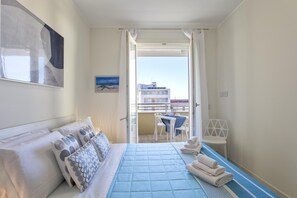 A hotel room with a bed, a desk, and a view of the balcony. - Coro e Bentu 1 Bedrooms Apartment in Alghero (Alghero)