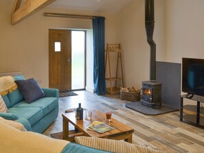 Una sala de estar con un sofá, una mesa de centro de madera, un televisor, una chimenea y una puerta que da al exterior.