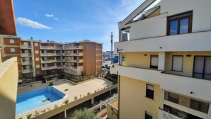 Edifício residencial com várias varandas, piscina e vista para uma torre ao fundo.