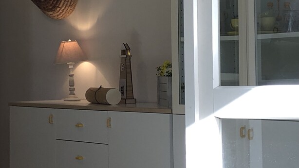Uma cozinha com um armário branco, uma luminária e um objeto decorativo no balcão.