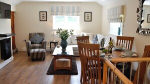 A living room with a sofa, chairs, a dining table, and a fireplace. - 2 bedroom accommodation in Brampton, near Carlisle (Brampton, near Carlisle)