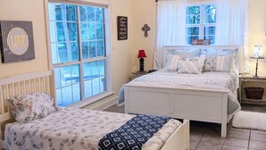 Ein Schlafzimmer mit zwei Betten, einem Deckenventilator und einem Fenster mit Vorhängen.