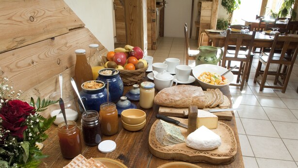 A wooden table with various food items, including bread, cheese, and fruits.
