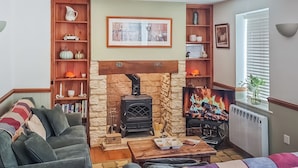 Un salon chaleureux avec une cheminée, des étagères à livres et un coin salon confortable.