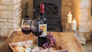 Un plateau en bois avec une bouteille de vin, deux verres et une grappe de raisins, le tout posé sur une table.