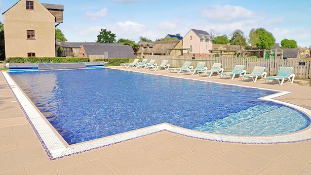 Une piscine avec des chaises longues et un bâtiment en arrière-plan.