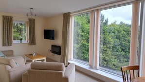 Una sala de estar con sofá, una mesita, televisor y chimenea.