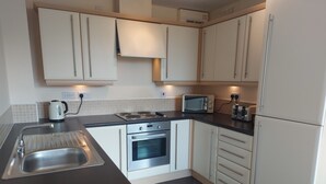 Una cocina moderna con electrodomésticos de acero inoxidable, armarios blancos y una encimera negra.