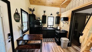 A compact kitchen with wooden flooring, a dining table, and a built-in stove.
