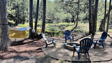 Un camping con una hamaca, un pozo para fuego y varias sillas Adirondack.