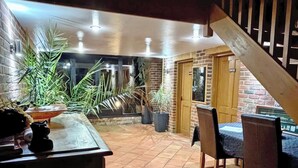 A patio area with a table and chairs, potted plants, and a brick wall.