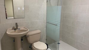 Un baño con inodoro, lavamanos y cabina de ducha de vidrio.