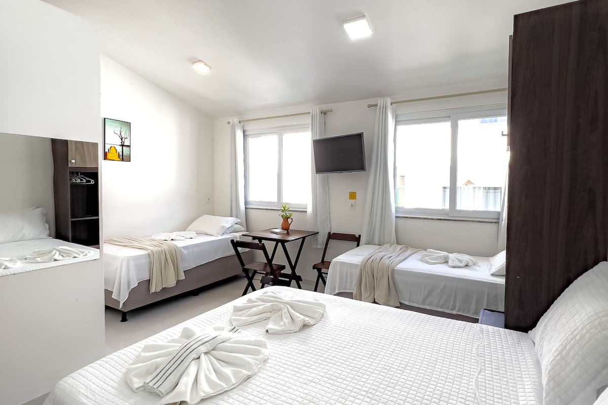 Ein Hotelzimmer mit zwei Betten, einem Schreibtisch, einem Fernseher und einem Fenster mit Vorhängen.