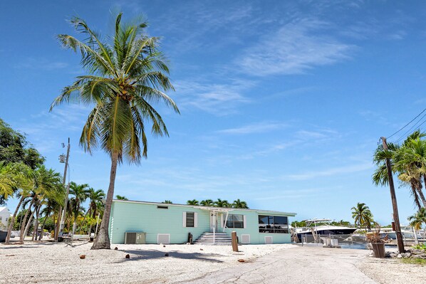 A small, single-story building with a light blue exterior, surrounded by palm trees. - Paradise on main canal with spectacular sunset (Key Largo)
