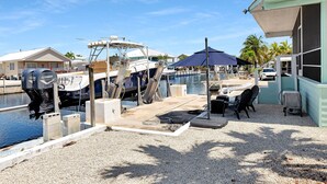A marina with boats docked, a covered seating area, and a small building with a green roof. - Paradise on main canal with spectacular sunset (Key Largo)