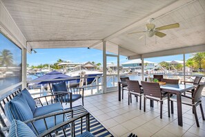 A covered outdoor seating area with wicker furniture, a table, and a ceiling fan. - Paradise on main canal with spectacular sunset (Key Largo)