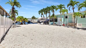 A beachfront property with palm trees, a pool, and a building with a light green facade. - Paradise on main canal with spectacular sunset (Key Largo)