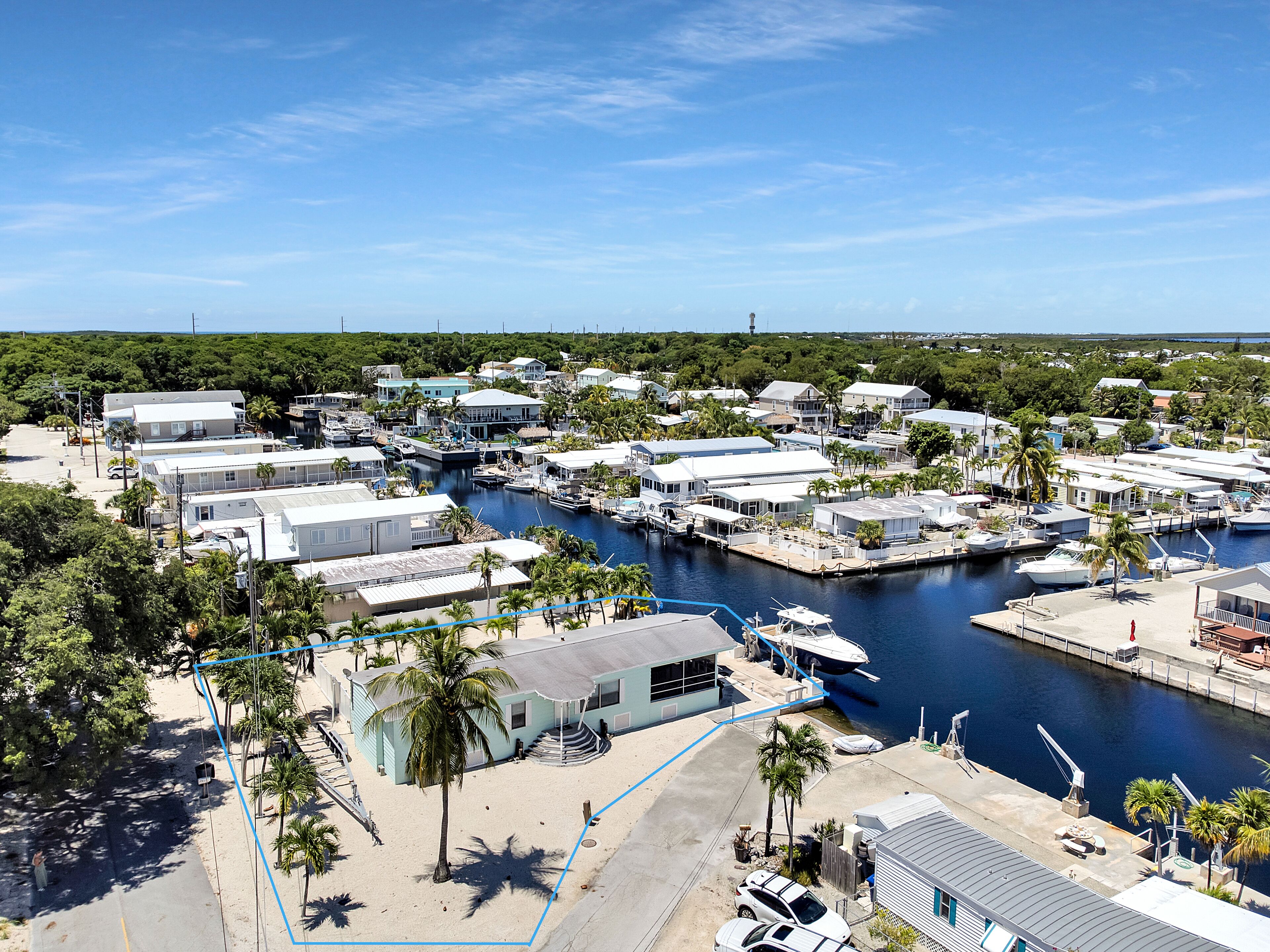 A marina with boats docked, surrounded by residential buildings and palm trees.