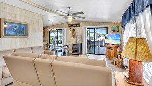 A spacious living area with a beige sofa, a ceiling fan, a television, and a wooden sign reading "MORALES". - Paradise on main canal with spectacular sunset (Key Largo)