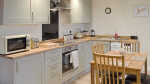 A modern kitchen with a microwave, oven, sink, and wooden dining table. - 2 bedroom accommodation in Alkham, near Dover (Alkham, near Dover)