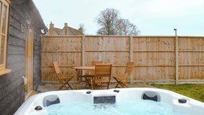 A hot tub with a wooden table and chairs, surrounded by a wooden fence and a house. - 2 bedroom accommodation in Alkham, near Dover (Alkham, near Dover)