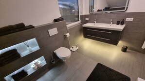 Une salle de bain moderne équipée de toilettes, d’un lavabo et d’un porte-serviettes intégré.